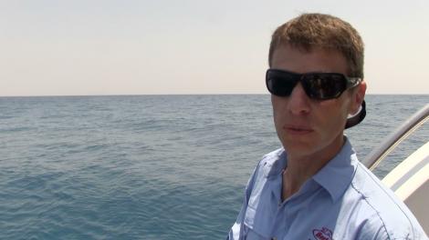 Dr Glenn Moore fishing from the back of the Kimberley Quest boat wearing sunglasses